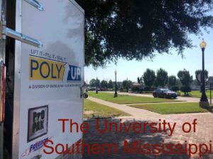 The University of Southern Mississippi campus with buildings and greenery under a clear blue sky.