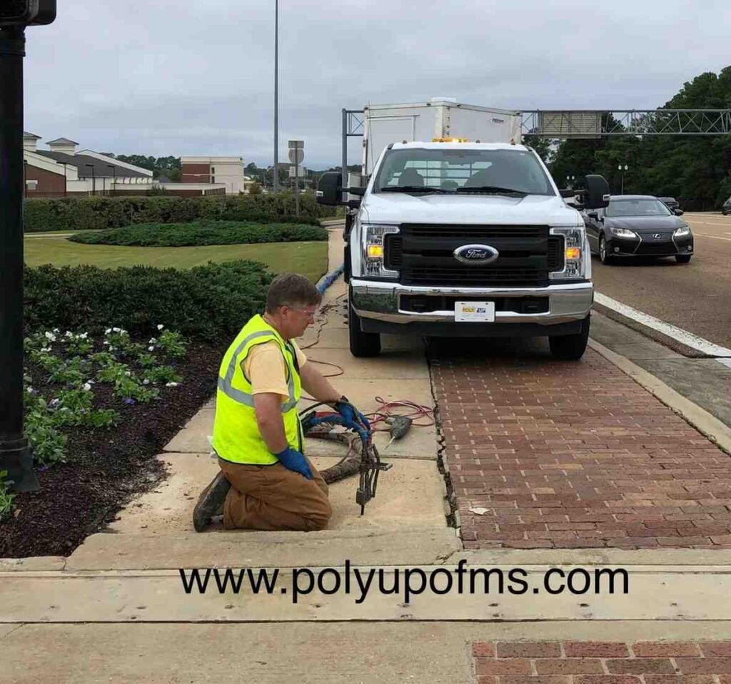 A man is kneeling next to a truck, engaged in an activity on the ground.